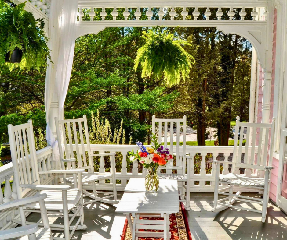 Sun lit porch with five wooden rocker chairs